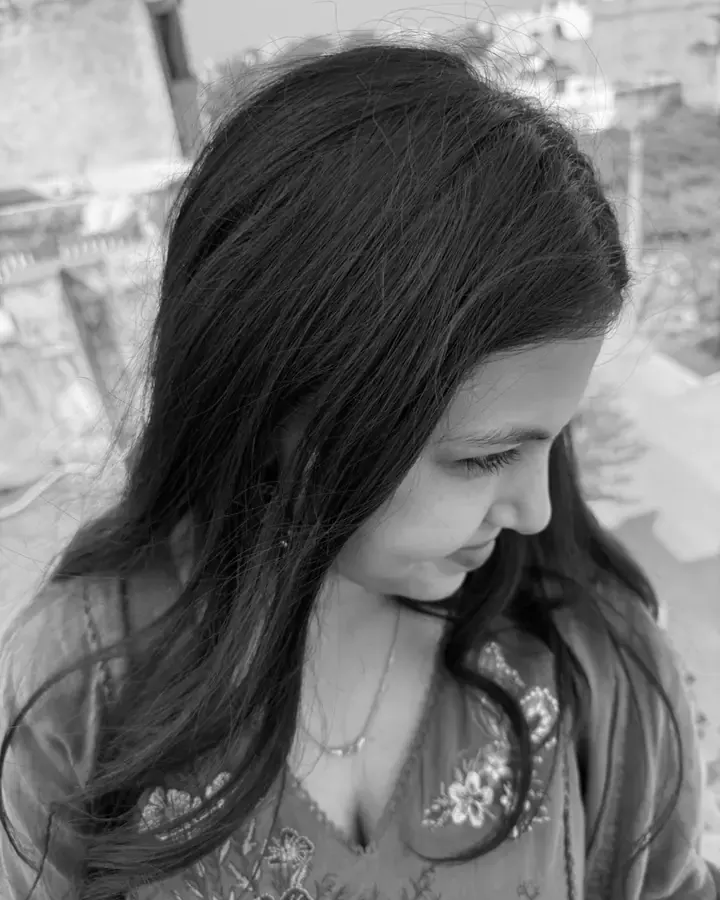 Bhumika on a rooftop, looking down and smiling